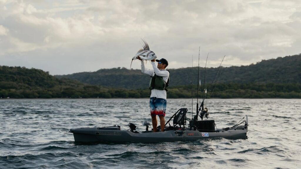 Wędkarz spinningujący z pozycji stojącej na stabilnym kajaku marki Native – dlaczego warto wybrać markowy sprzęt zamiast taniego zamiennika.