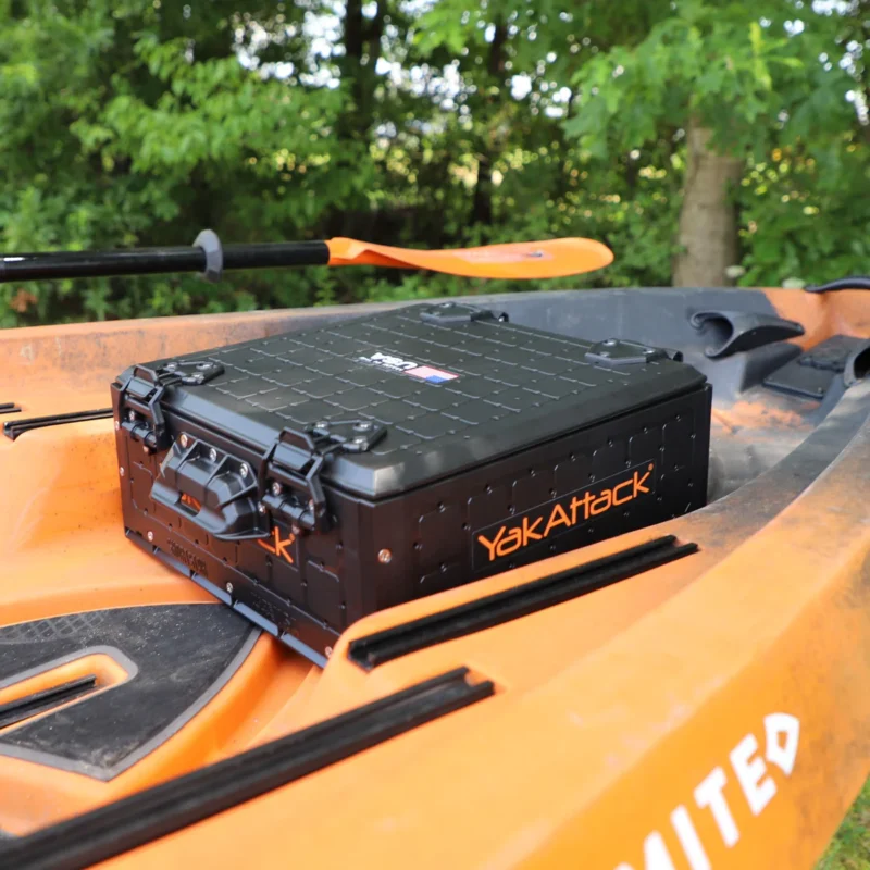 Czarne pudełko YakAttack ShortStak SOLO wsunięte pod fotel na kajaku wędkarskim, funkcjonujące jako wygodna szuflada na akcesoria.