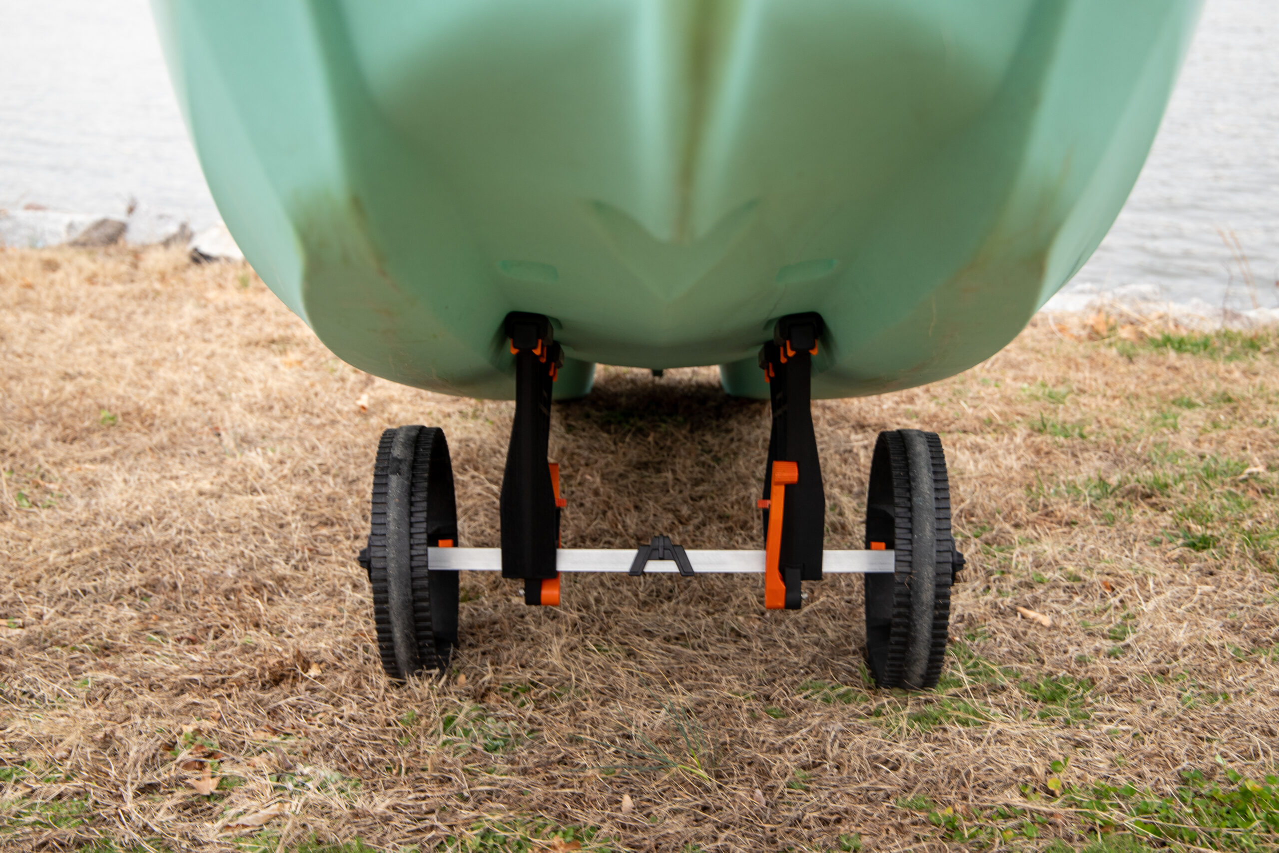 Widok od przodu pod kadłubem miętowego kajaka opierającego się na płozach wózka transportowego YakAttack TowNStow Bunkster Kayak Cart